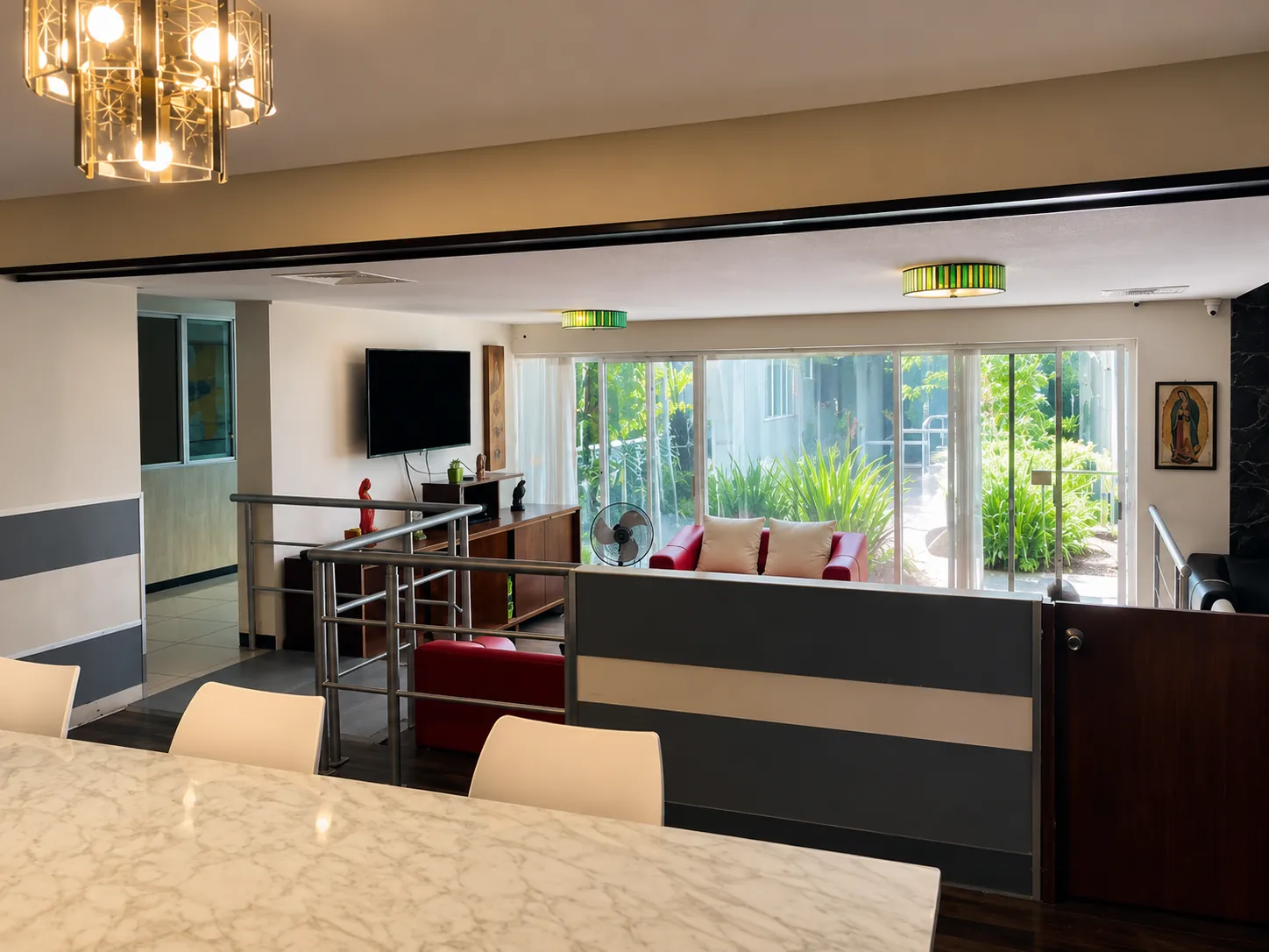 Sala de estar con televisión y vista al jardín en residencia para adultos mayores en Chihuahua